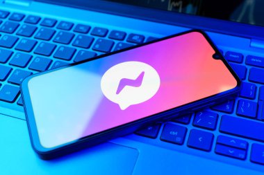 Prag, Çek Cumhuriyeti - 21 Ekim 2024: Laptop klavye arka planında kurye logosu gösteren modern akıllı telefon aygıtı.