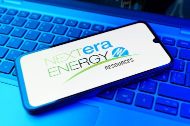 Prag, Çek Cumhuriyeti - 21 Ekim 2024: Laptop klavye arkaplanındaki modern akıllı telefon cihazı nextera enerji logosunu gösteriyor.