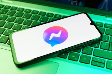 Prag, Çek Cumhuriyeti - 21 Ekim 2024: Laptop klavye arka planında Facebook kurye logosu gösteren modern akıllı telefon aygıtı.