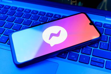 Prag, Çek Cumhuriyeti - 21 Ekim 2024: Laptop klavye arka planında Facebook kurye logosu gösteren modern akıllı telefon aygıtı.