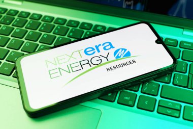 Prag, Çek Cumhuriyeti - 21 Ekim 2024: Laptop klavye arkaplanındaki modern akıllı telefon cihazı nextera enerji logosunu gösteriyor.