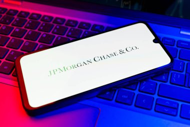 Prag, Çek Cumhuriyeti - 21 Ekim 2024: Laptop klavye arka planında JPMorgan Chase & co logosunu gösteren modern akıllı telefon aygıtı.