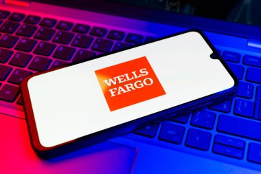 Prag, Çek Cumhuriyeti - 21 Ekim 2024: Laptop klavye arka planında Wells Fargo logosunu gösteren modern akıllı telefon aygıtı.