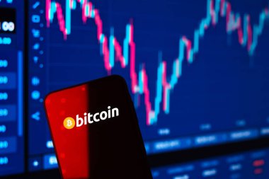Prag, Çek: Logo bitcoin 'li modern akıllı telefon arka planda grafikle ekranda 