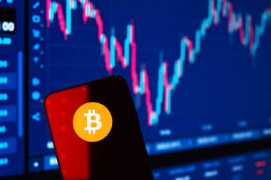 Prag, Çek: Logo bitcoin 'li modern akıllı telefon arka planda grafikle ekranda 