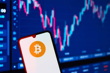 Prag, Çek: Logo bitcoin 'li modern akıllı telefon arka planda grafikle ekranda 