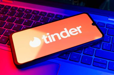 Prag, Çek Cumhuriyeti - 21 Ekim 2024: Laptop klavye arka planında Tinder logosu gösteren modern akıllı telefon aygıtı.