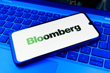 Prag, Çek Cumhuriyeti - 21 Ekim 2024: Laptop klavye arka planında Bloomberg logosunu gösteren modern akıllı telefon aygıtı.