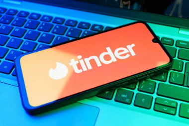 Prag, Çek Cumhuriyeti - 21 Ekim 2024: Laptop klavye arka planında Tinder logosu gösteren modern akıllı telefon aygıtı.