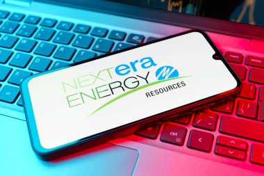 Prag, Çek Cumhuriyeti - 21 Ekim 2024: Laptop klavye arkaplanındaki modern akıllı telefon cihazı nextera enerji logosunu gösteriyor.