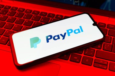 Prag, Çek Cumhuriyeti - 21 Ekim 2024: Laptop klavye arkaplanındaki modern akıllı telefon aygıtı paypal logoyu gösteriyor.