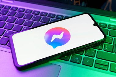 Prag, Çek Cumhuriyeti - 21 Ekim 2024: Laptop klavye arka planında Facebook kurye logosu gösteren modern akıllı telefon aygıtı.