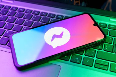 Prag, Çek Cumhuriyeti - 21 Ekim 2024: Laptop klavye arka planında Facebook kurye logosu gösteren modern akıllı telefon aygıtı.