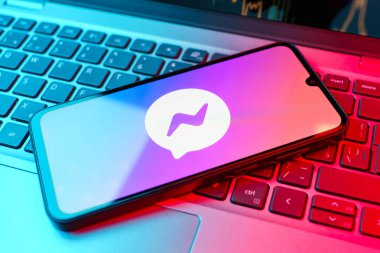 Prag, Çek Cumhuriyeti - 21 Ekim 2024: Laptop klavye arka planında Facebook kurye logosu gösteren modern akıllı telefon aygıtı.