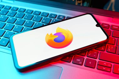 Prag, Çek Cumhuriyeti - 21 Ekim 2024: Laptop klavye arka planında mozilla fireofx logosu gösteren modern akıllı telefon aygıtı.