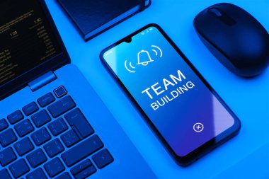 Ofis masasında bilgisayar faresi ve dizüstü bilgisayarlı akıllı telefon ekranda metni gösteriyor