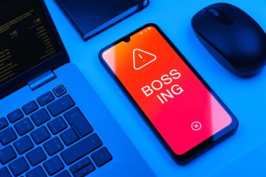 Ofis masasında bilgisayar faresi ve dizüstü bilgisayarlı modern akıllı telefon ekranda patronluk taslayan metni gösteriyor