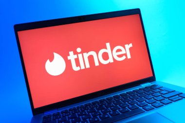 Prag, Çek Cumhuriyeti - 05 08 2025: Renkli bir arkaplanda uzanan ve Tinder logosunu gösteren bir dizüstü bilgisayarın yakından görüntüsü.
