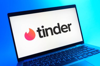 Prag, Çek Cumhuriyeti - 05 08 2025: Renkli bir arkaplanda uzanan ve Tinder logosunu gösteren bir dizüstü bilgisayarın yakından görüntüsü.