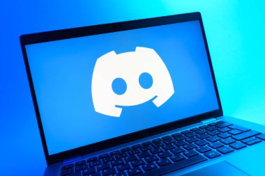 Prag, Çek Cumhuriyeti - 05 08 2025: Renkli arkaplanda yatan ve Discord logosunu gösteren bir dizüstü bilgisayarın yakından görüntüsü.