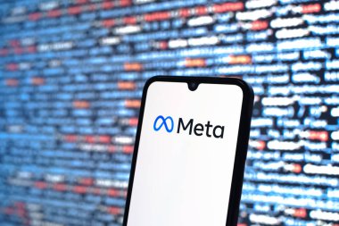 Prag, Çek Cumhuriyeti - 05: 18 2025: Kaynak kod arkaplanı önündeki akıllı telefon Meta logosunu görüntüler.