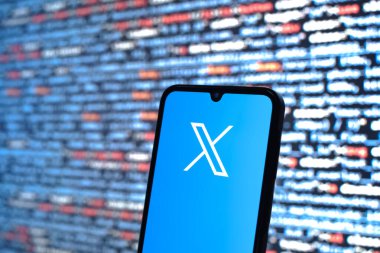 Prag, Çek Cumhuriyeti - 05: 18 2025: Kaynak kod arkaplanının önündeki akıllı telefon X logosunu gösterir.