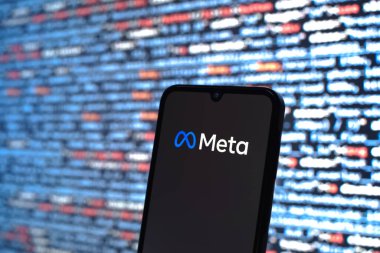 Prag, Çek Cumhuriyeti - 05: 18 2025: Kaynak kod arkaplanı önündeki akıllı telefon Meta logosunu görüntüler.
