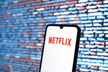 Prag, Çek Cumhuriyeti - 05: 18 2025: Kaynak kod arkaplanı önündeki bir akıllı telefon Netflix logosunu görüntüler.