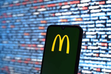 Prag, Çek Cumhuriyeti - 05: 18 2025: Kaynak kod arkaplanı önündeki bir akıllı telefon McDonalds logosunu görüntüler.