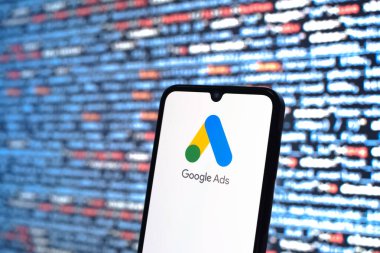 Prag, Çek Cumhuriyeti - 05: 18 2025: Kaynak kod arkaplanı önündeki bir akıllı telefon Google Ads logosunu görüntüler.