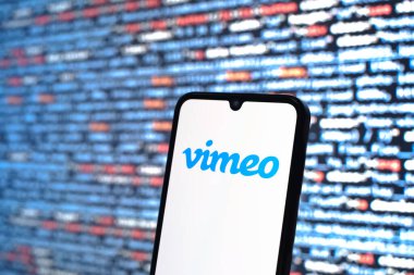 Prag, Çek Cumhuriyeti - 05: 18 2025: Kaynak kod arkaplanı önündeki akıllı telefon Vimeo logosunu görüntüler.