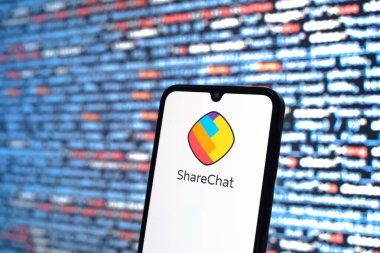 Prag, Çek Cumhuriyeti - 05: 18 2025: Kaynak kod arkaplanı önündeki bir akıllı telefon ShareChat logosunu görüntüler.