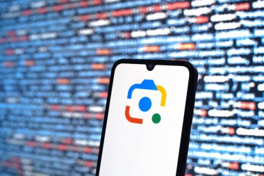 Prag, Çek Cumhuriyeti - 05: 18 2025: Kaynak kod arkaplanı önündeki bir akıllı telefon Google Lens logosunu görüntüler.