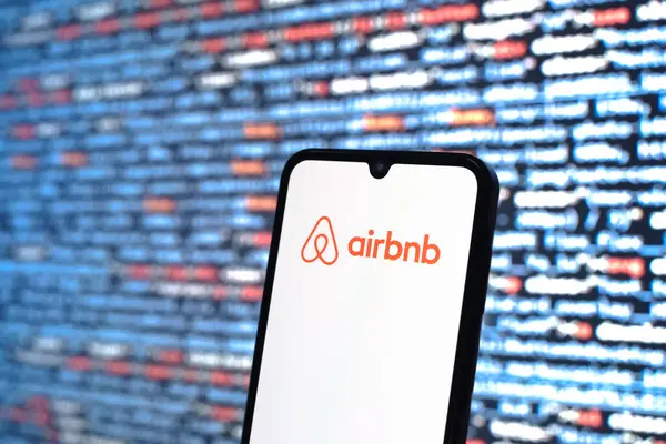 Prag, Çek Cumhuriyeti - 05: 18 2025: Kaynak kod arkaplanı önündeki bir akıllı telefon Airbnb logosunu görüntüler.