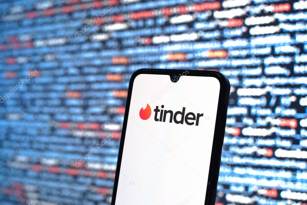 Prague, Czechia - 05 18 2025: A smartphone in front of source code background displays Tinder logo.
