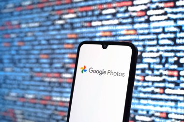Prag, Çek Cumhuriyeti - 05: 18 2025: Kaynak kod arkaplanı önündeki bir akıllı telefon Google Fotoğrafları logosunu görüntüler.
