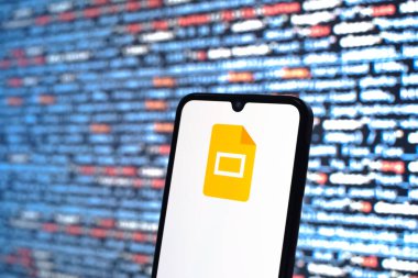 Prag, Çek Cumhuriyeti - 05: 18 2025: Kaynak kod arkaplanı önündeki bir akıllı telefon Google Slayt logosunu görüntüler.