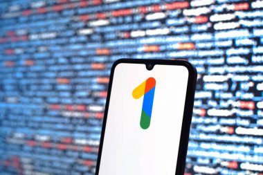 Prag, Çek Cumhuriyeti - 05: 18 2025: Kaynak kod arkaplanı önündeki bir akıllı telefon Google One logosunu görüntüler.
