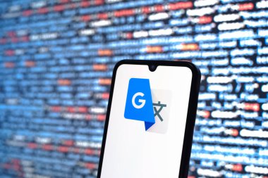Prag, Çek Cumhuriyeti - 05: 18 2025: Kaynak kod arkaplanı önündeki bir akıllı telefon Google Translate logosunu görüntüler.