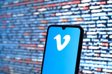 Prag, Çek Cumhuriyeti - 05: 18 2025: Kaynak kod arkaplanı önündeki akıllı telefon Vimeo logosunu görüntüler.