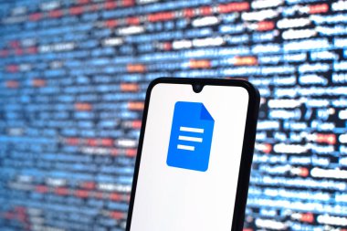 Prag, Çek Cumhuriyeti - 05: 18 2025: Kaynak kod arkaplanı önündeki bir akıllı telefon Google Docs logosunu görüntüler.