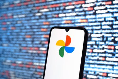 Prag, Çek Cumhuriyeti - 05: 18 2025: Kaynak kod arkaplanı önündeki bir akıllı telefon Google Fotoğrafları logosunu görüntüler.