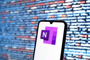 Prag, Çek Cumhuriyeti - 05: 18 2025: Kaynak kod arkaplanı önündeki bir akıllı telefon Microsoft OneNote logosunu görüntüler.