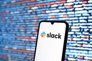 Prag, Çek Cumhuriyeti - 05: 18 2025: Kaynak kod arkaplanı önündeki bir akıllı telefon Slack logosunu görüntüler.