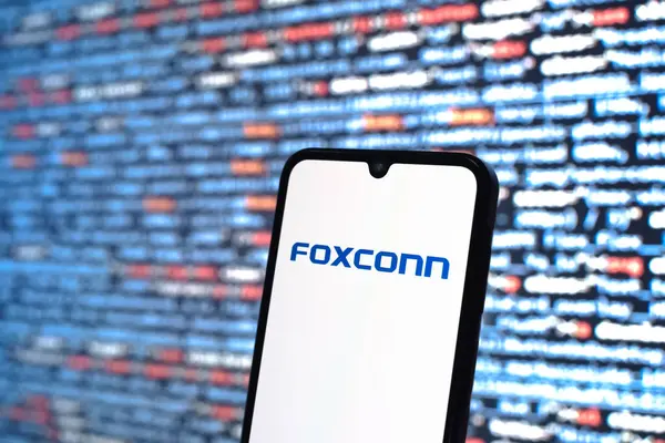 Prag, Çek Cumhuriyeti - 05: 18 2025: Kaynak kod arkaplanı önündeki bir akıllı telefon Foxconn logosunu görüntüler.