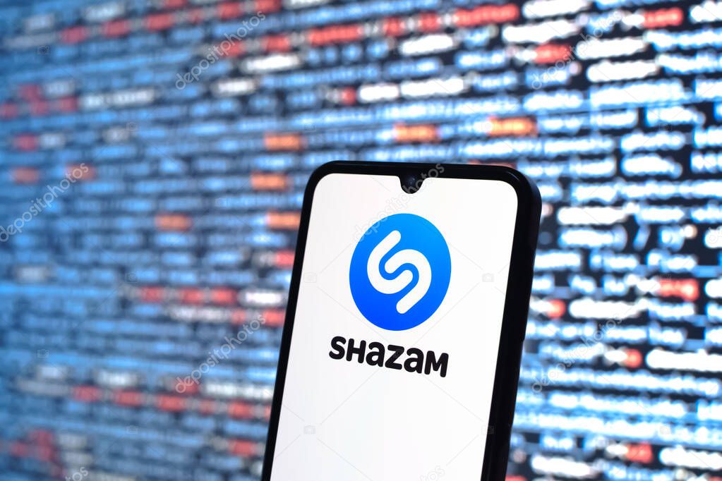 Prague, Czechia - 05 18 2025: A smartphone in front of source code background displays Shazam logo.