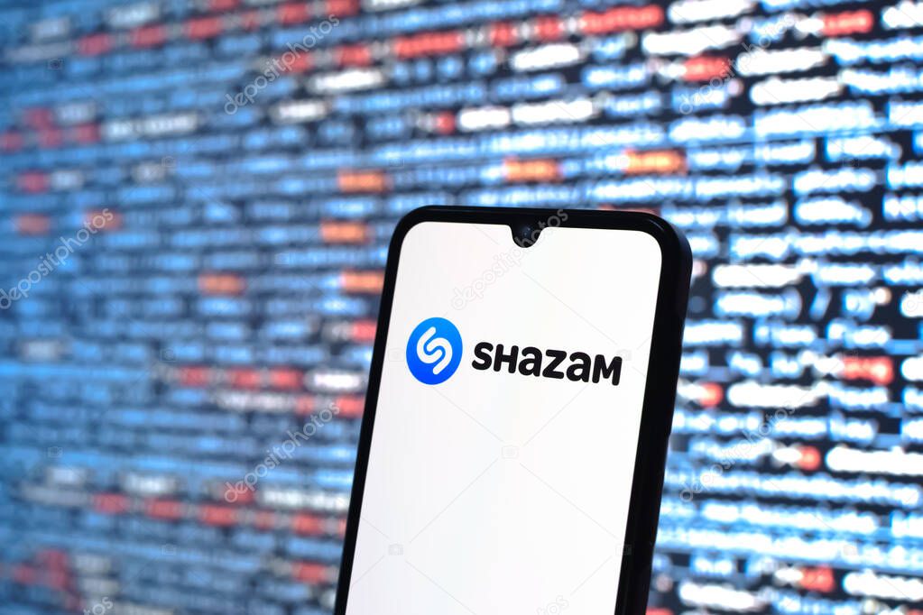 Prague, Czechia - 05 18 2025: A smartphone in front of source code background displays Shazam logo.