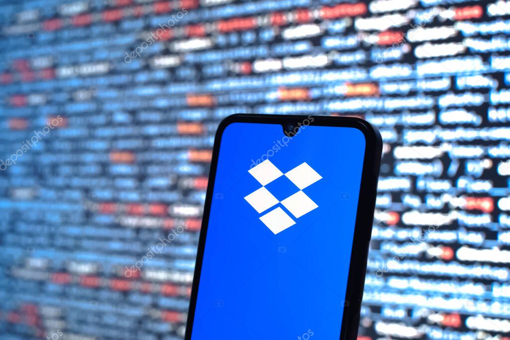 Prague, Czechia - 05 18 2025: A smartphone in front of source code background displays Dropbox logo.