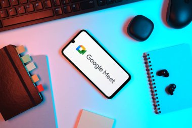 Prag, Çek Cumhuriyeti - 05: 18 2025: Google Meet logosunu gösteren bir telefonla ofis masasına yerleştirilmiş nesneler.