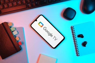 Prag, Çek Cumhuriyeti - 05: 18 2025: Google TV logosunu gösteren bir telefonla ofis masasına yerleştirilmiş nesneler.